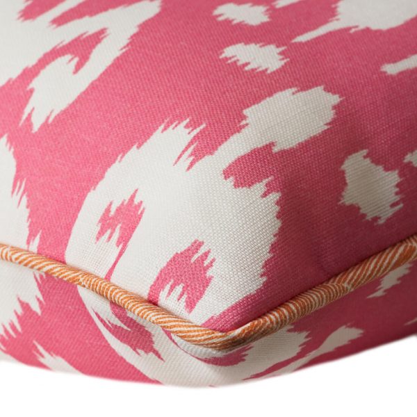 Outdoor cushion in vibrant pink ikat design with orange piping